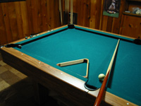 photo of a pool table, rack, cue and cue ball